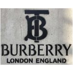 Black spray painted Burberry TB monogram and logo stencil on a textured concrete wall.